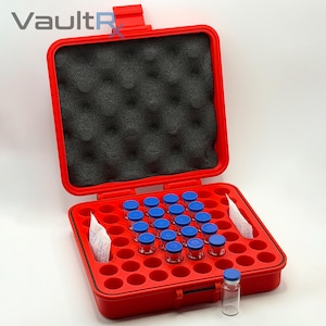 May include: Open red case with a black foam interior and a grid of circular compartments. The case contains small glass vials with blue caps. A single vial sits outside the case. The logo "VaultRx" is visible in the upper left corner.