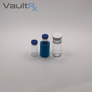 May include: Three clear glass vials with blue and white caps. One vial is in a blue holder. The vials are of varying sizes and are empty. The text "VaultRx" is in the upper left corner.
