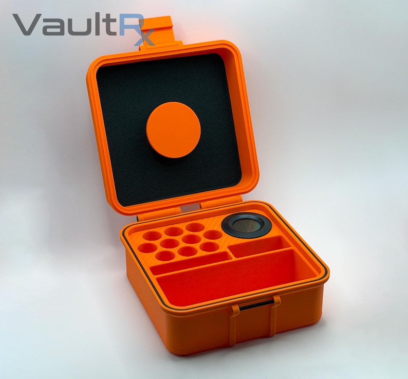 May include: Open orange storage case with black interior foam and a circular orange lid. The case has multiple compartments and a black circular insert. The case is designed to protect and organize small items.