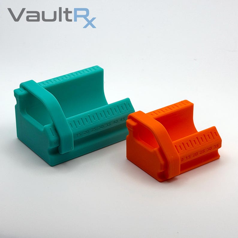 May include: Two brightly colored, teal and orange, plastic measuring tools. Each tool has a curved cradle shape with a handle and a ruler printed on the side, marked in increments. The text "VaultRx" is in the upper left corner.