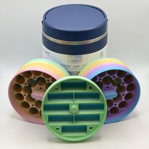 May include: A stainless steel insulated food jar with a navy blue lid and a silver band. Three multi-colored, circular, 3D-printed components are in front of the jar. The text on the jar reads "FOOD JAR 32oz".