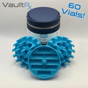 May include: A navy blue insulated food jar with a silver band, accompanied by three light blue vial holders. The text "60 Vials!" is visible. The jar is labeled "FOOD JAR 32oz". The brand name "VaultRx" is in the upper left corner.