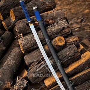 May include: A katana sword with a blue handle and a black scabbard rests on a pile of wooden logs. The blade is silver, and the handle is wrapped in blue fabric. The scabbard is black with a silver accent. The text "USACRAFTSKNIFE" is visible.