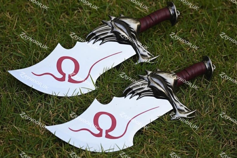 May include: Two silver and white blades with a red Omega symbol on the blade. The handles are wrapped in burgundy leather. The blades are lying on a bed of green grass.