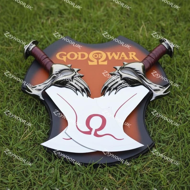 May include: A decorative shield featuring two silver and white blades with red handles, set against a brown and black backdrop. The shield has the words "GOD OF WAR" in orange. The blades have a red Omega symbol.