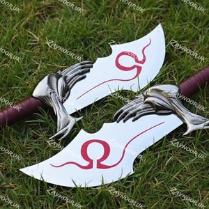 May include: Two fantasy-style blades with curved, silver blades and burgundy handles. The blades feature a red design and a hand-shaped guard. The blades are displayed on a bed of green grass.