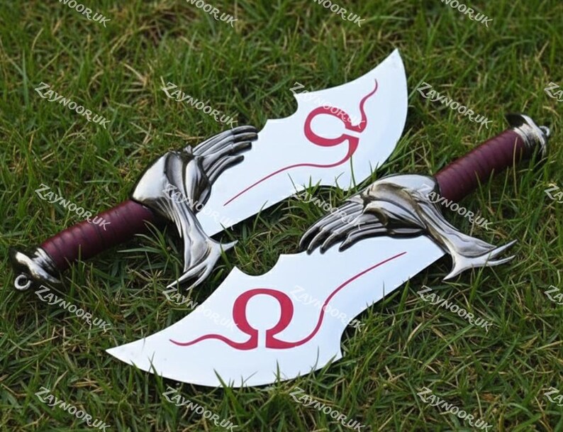May include: Two fantasy-style blades with curved, silver blades and burgundy handles. The blades feature a red design and a hand-shaped guard. The blades are displayed on a bed of green grass.