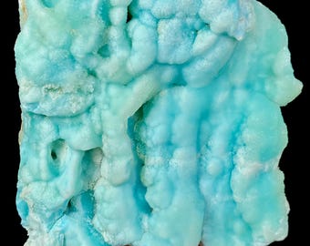 Op de afbeelding: Een close-up van een stuk blauw aragoniet mineraal. Het aragoniet heeft een bubbelige, getextureerde oppervlakte met verschillende tinten blauw en turquoise. Het mineraal wordt tegen een zwarte achtergrond gehouden.