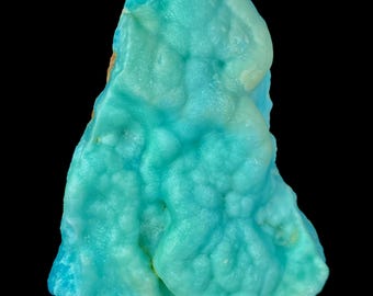 May include: A close-up of a vibrant, textured mineral specimen. The stone features a striking blend of turquoise and light blue hues, with a bubbly, organic surface. The mineral is set against a black background, highlighting its unique color and form.