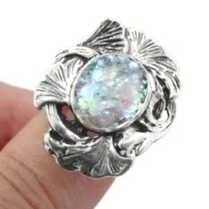 以下が含まれることがあります： 葉っぱのデザインに大きな虹色の楕円形の石がセットされた銀の指輪