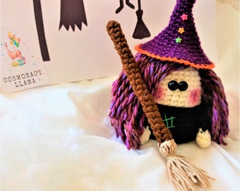 May include: A crocheted witch doll with purple hair, a purple hat with orange trim and stars, and a brown broom. The doll is sitting on a white surface.