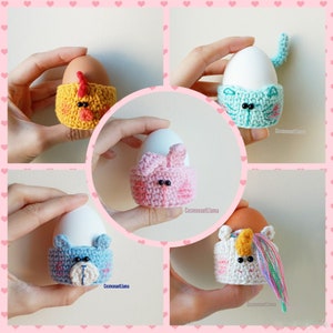 May include: A collage of five crocheted egg cozies, each designed as a different animal: a yellow chicken, a blue bear, a pink bunny, a blue cat, and a white unicorn. Each cozy holds an egg. The background is a light pink with heart shapes.