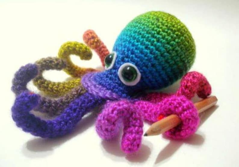 May include: A rainbow crocheted octopus with green eyes and a pencil in one of its tentacles.
