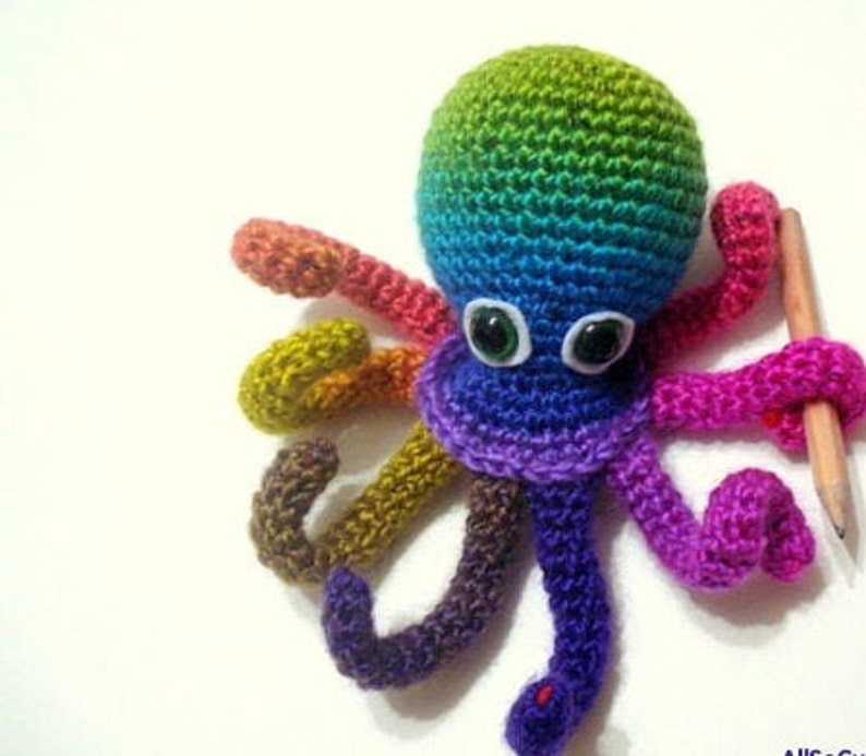 May include: A rainbow crocheted octopus with large green eyes. The octopus has eight tentacles, each a different color of the rainbow.