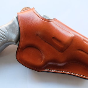 May include: A brown leather holster for a silver handgun.