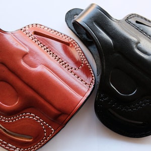 May include: Two leather holsters for handguns, one brown and one black. Both holsters have a stitched design and are made of high-quality leather.