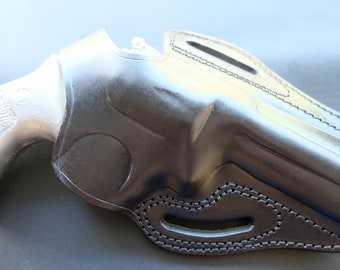May include: A black leather holster for a handgun. The holster has a belt loop and a thumb break.