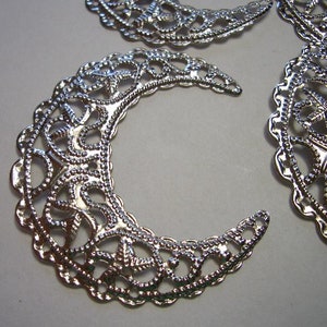 May include: Three silver-toned metal filigree components shaped like crescent moons. Each piece features an intricate, openwork pattern with small, raised beaded textures along the edges and throughout the delicate, swirling design.