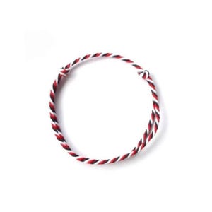 May include: A braided bracelet featuring red, black, and white threads. The bracelet is circular and appears to be handmade. The design is simple and the colors are bold, making it a versatile accessory.