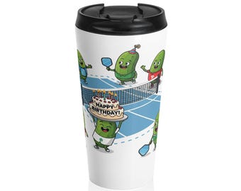 Könnte beinhalten: Weißer Reisebecher mit einem Cartoon-Pickleball-Design. Animierte Gurken spielen Pickleball, eine davon hält einen Kuchen mit der Aufschrift "Happy Birthday!". Der Becher hat einen schwarzen Deckel und ist für heiße oder kalte Getränke geeignet.