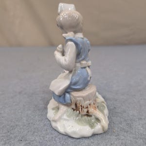 Statuetta vintage in porcellana raffigurante un'infermiera con un cucciolo in un cestino, nei colori blu e bianco. immagine 3