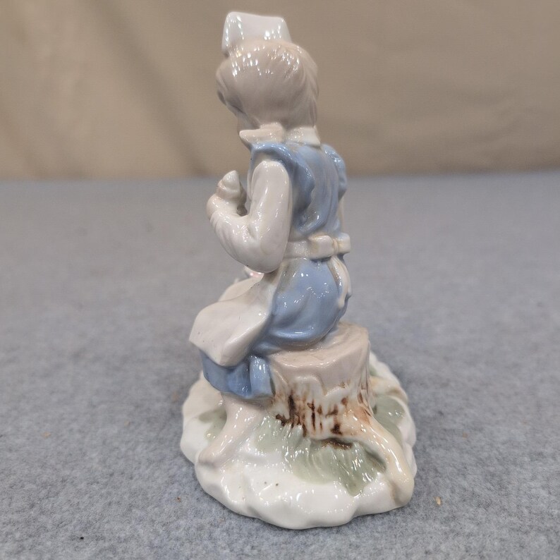 Statuetta vintage in porcellana raffigurante un'infermiera con un cucciolo in un cestino, nei colori blu e bianco. immagine 3