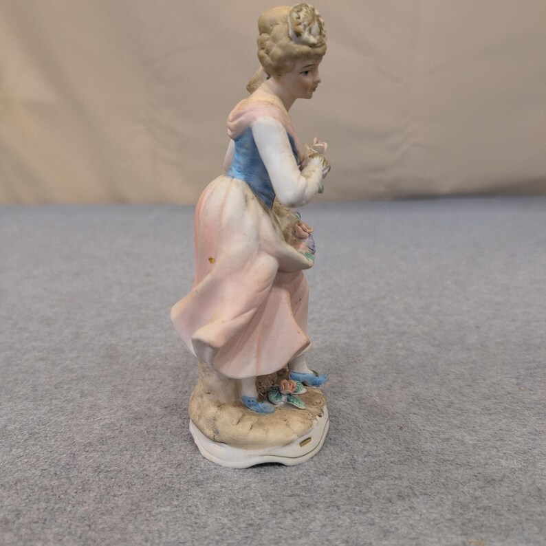 Estatueta vintage de porcelana biscuit representando uma mulher com uma cesta de flores em tons de rosa, azul e branco. imagem 2