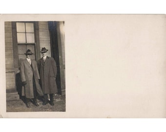 Cartão postal fotográfico vintage RPPC com foto real de dois homens de sobretudo e chapéu fedora, caixa de selos Cyko.