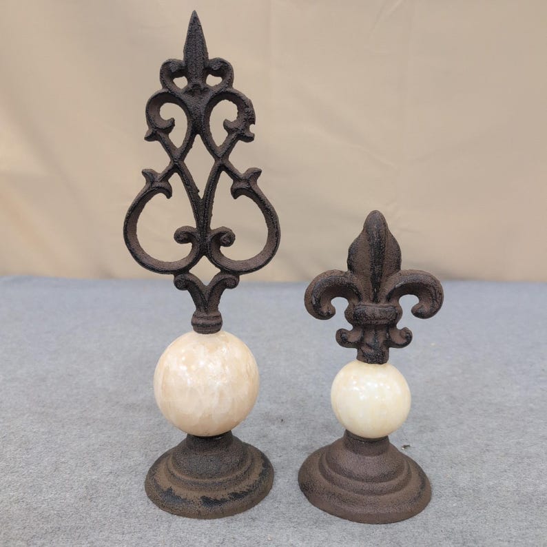 Juego de 2 remates decorativos de hierro fundido y piedra con diseño de flor de lis, color marrón crema. imagen 1