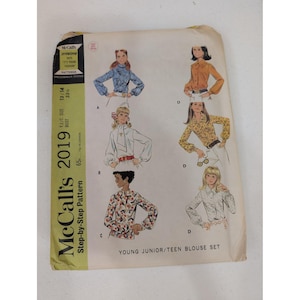 Puede incluir: Patrón de costura vintage McCall's 2019 para un conjunto de blusas para jóvenes/adolescentes. El sobre del patrón presenta ilustraciones de blusas en varios estilos, incluyendo diseños florales azules, naranjas y estampados. Contorno de busto 84 cm.