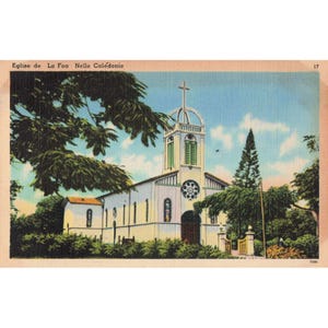 May include: Vintage postcard featuring the Eglise de La Foa in New Caledonia. The white church has a tall steeple with a cross, a round window, and green shutters. Lush green trees and foliage surround the building under a blue sky.