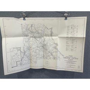 May include: A folded, vintage map of Chilton County, Alabama, held by metal clips. The map, printed in black ink on off-white paper, displays roads, towns, and geographical features. Text includes "General Highway Map" and "Alabama Highway Department."