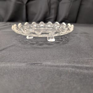Vintage onderzetter van helder geperst glas met honingraatmotief, geschulpte rand en zonnestralenmotief in het midden. afbeelding 2