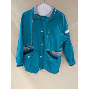 May include: Teal-colored jacket with a white and plaid collar and pocket accents. The jacket features a button-up front, two front pockets, and a drawstring hem. The sleeves have navy blue cuffs. A white stripe is on the right sleeve.
