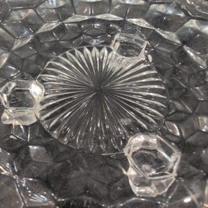 Vintage onderzetter van helder geperst glas met honingraatmotief, geschulpte rand en zonnestralenmotief in het midden. afbeelding 5