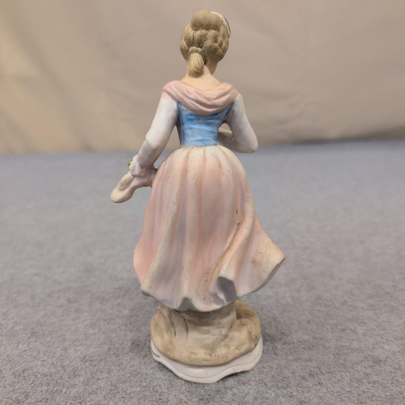 Estatueta vintage de porcelana biscuit representando uma mulher com uma cesta de flores em tons de rosa, azul e branco. imagem 3