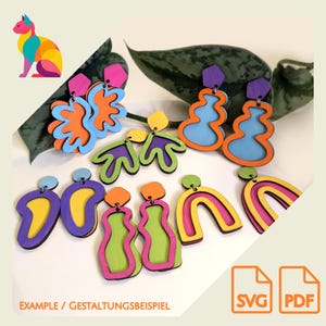 Könnte beinhalten: Eine Auswahl an bunten, geschichteten Holzohrringen in verschiedenen abstrakten Formen. Designs umfassen Blumen, Wellenformen und Regenbogen, mit Farben wie Blau, Orange, Gelb, Lila und Grün. Der Text "EXAMPLE / GESTALTUNGSBEISPIEL" ist sichtbar.