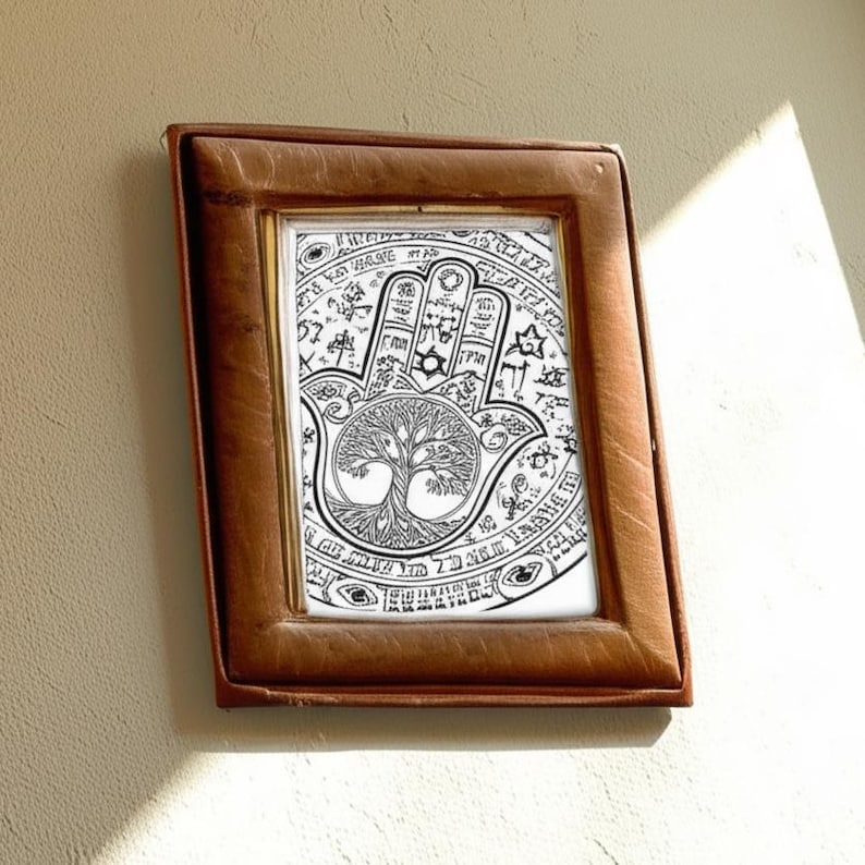 Puede incluir: Una impresi&oacute;n art&iacute;stica en blanco y negro enmarcada de una mano de Hamsa. La obra de arte presenta una ilustraci&oacute;n detallada de una mano con un ojo en la palma, rodeada de s&iacute;mbolos y un dise&ntilde;o de &aacute;rbol de la vida. El marco es de color marr&oacute;n c&aacute;lido.