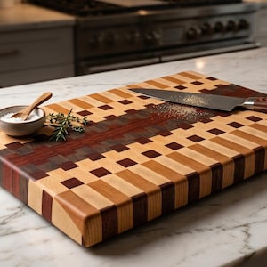 May include: A rectangular wooden cutting board featuring a multi-colored checkerboard pattern of light, medium, and dark wood blocks. A stainless steel chef knife with a wood handle rests on the surface, alongside a small bowl with a wooden spoon.