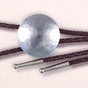 May include: A silver bolo tie with a round, hammered metal pendant and brown braided leather cord.