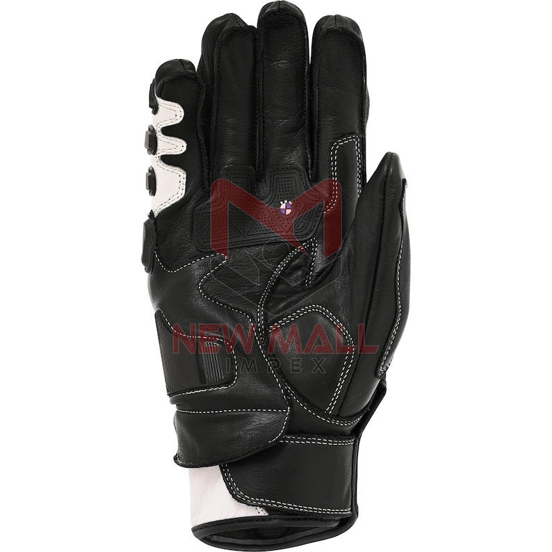 May include: Black and white motorcycle glove with reinforced padding and stitching. The glove features a white accent design on the back of the hand and wrist, with the brand name "NEW MALL IMPEX" visible.