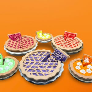May include: A collection of colorful toy pies with various fillings and crust designs. The pies are arranged on white plates against an orange background. Each pie has a slice removed, showcasing the different fillings.