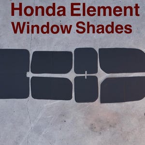 May include: A set of black window shades for a Honda Element, arranged on a gray surface. The text "Honda Element Window Shades" is displayed in red at the top of the image. The shades are cut to fit various windows.