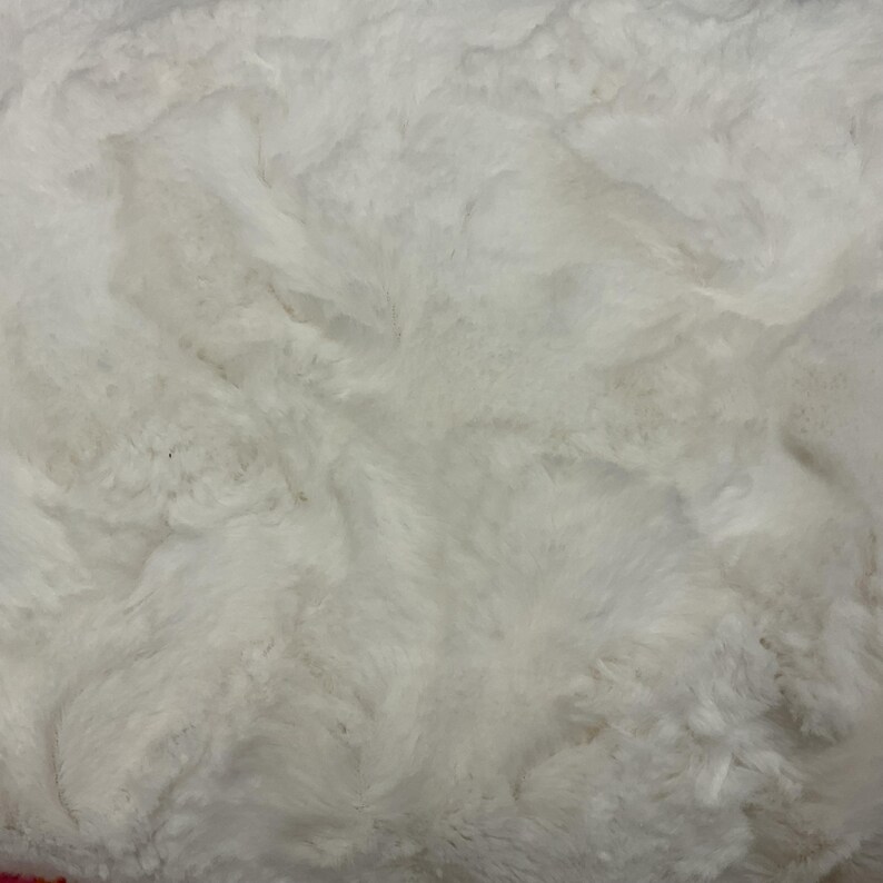 Puede incluir: Primer plano de una tela de piel sint&eacute;tica blanca, suave y texturizada. La tela tiene un patr&oacute;n ondulado, lo que le da un aspecto afelpado y lujoso. Ideal para mantas, mantas o ropa, el material es suave y acogedor.