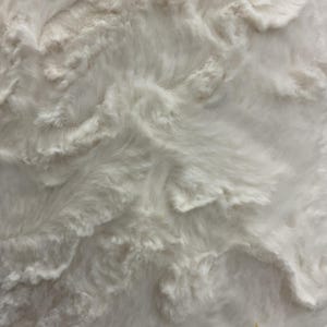 Puede incluir: Primer plano de una tela blanca texturizada con un aspecto suave y afelpado. El material tiene un patr&oacute;n ondulado en forma de nube, creando una sensaci&oacute;n de profundidad y dimensi&oacute;n. La textura de la tela sugiere una sensaci&oacute;n acogedora y c&oacute;moda, adecuada para mantas o colchas.