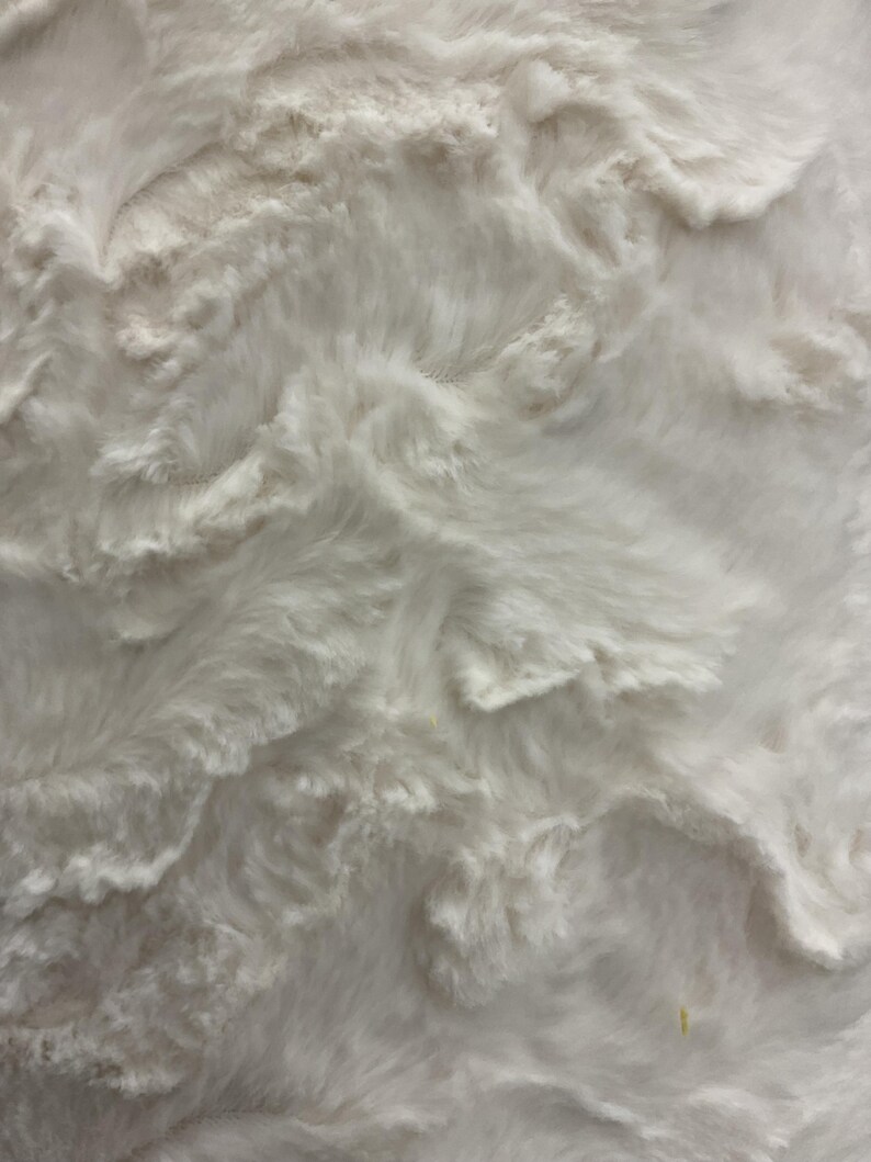 Puede incluir: Primer plano de una tela blanca texturizada con un aspecto suave y afelpado. El material tiene un patr&oacute;n ondulado en forma de nube, creando una sensaci&oacute;n de profundidad y dimensi&oacute;n. La textura de la tela sugiere una sensaci&oacute;n acogedora y c&oacute;moda, adecuada para mantas o colchas.