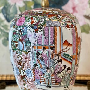 May include: A porcelain ginger jar featuring a hand-painted scene of figures in traditional attire within an architectural setting. The vessel is decorated with vibrant floral motifs, gold accents, and a pointed lid, showcasing a detailed polychrome design.