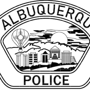 May include: Black and white Albuquerque Police badge. The design features a hot air balloon, buildings, and a sun, with the word "ALBUQUERQU" at the top and "POLICE" at the bottom.