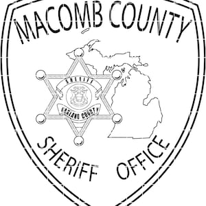 May include: Black and white Macomb County Sheriff Office badge. The badge features the words "Macomb County Sheriff Office" and a six-pointed star with the words "Sheriff" and "Oakland County". A map of Michigan is also included.