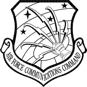 Può includere: Emblema in bianco e nero dell'Air Force Communications Command. Il design a forma di scudo presenta stelle, fulmini e un dispositivo di comunicazione stilizzato, con un banner alla base.